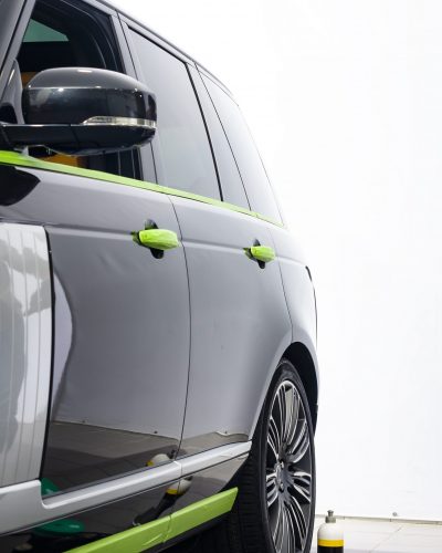 Car in applying green protective tape before polishing. Buffing and polishing car. Car detailing. Car service. Tools for polishing