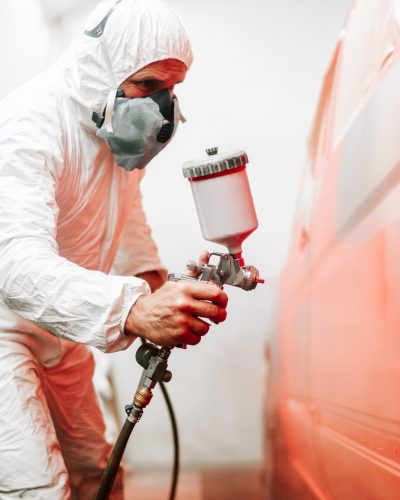 close up details of industrial worker, mechanic engineer using a paint gun and painting a car