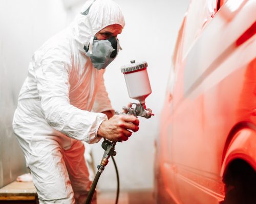 close up details of industrial worker, mechanic engineer using a paint gun and painting a car